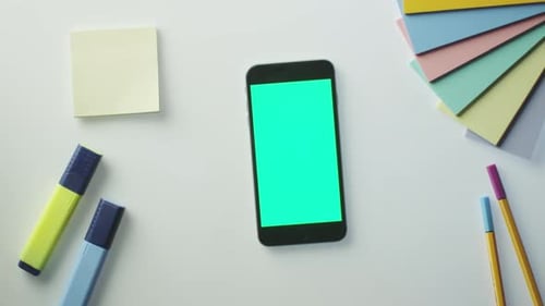 O designer está usando o celular com tela verde no modo retrato. Vista superior.