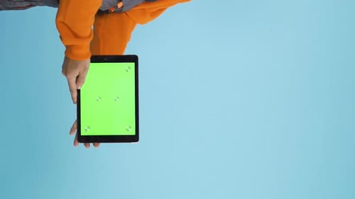 Man Holding a Tablet with Green Screen Mock Up Copy Space and Blue Background