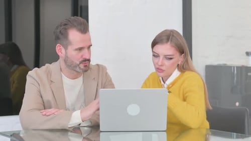Man and Woman Collaborating on Laptop at Desk