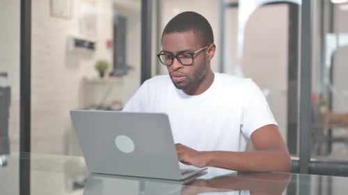 Focused Man Typing on Laptop in Office