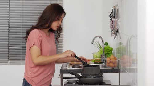 Young Woman Cooking in Bright Kitchen at Home