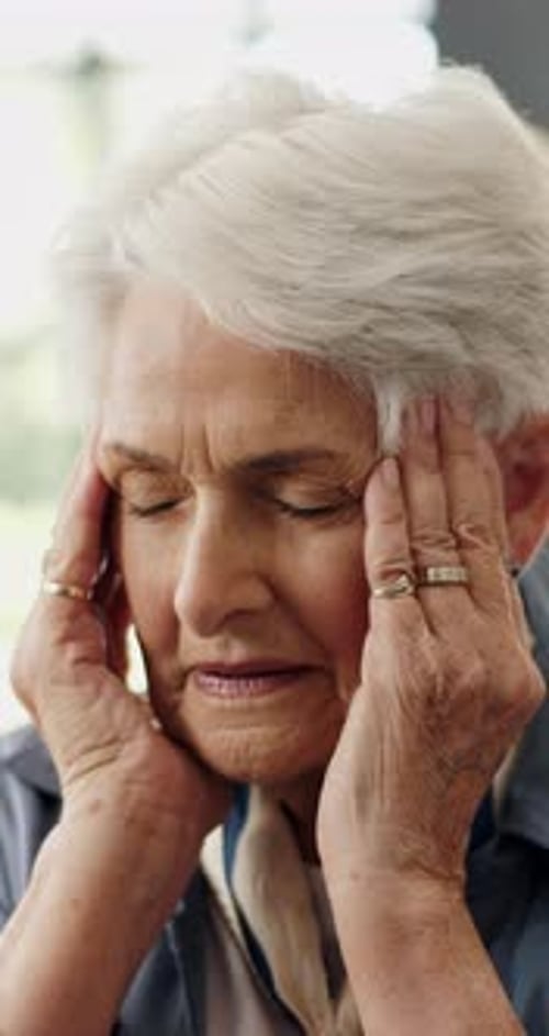Senior woman, headache and stress in home with temple massage, fatigue or pressure in lounge
