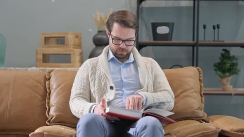 Man Reading a Book on a Couch Indoors