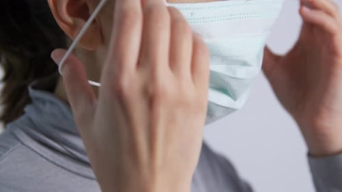 Woman Puts On Protective Face Mask Close Up