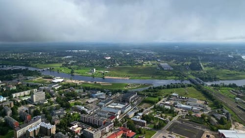 Aerial view of a green city with a river and a bridge on a cloudy day
