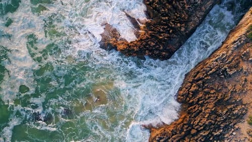 Aerial Top Down View of Ocean Waves Crashing Against Rocks