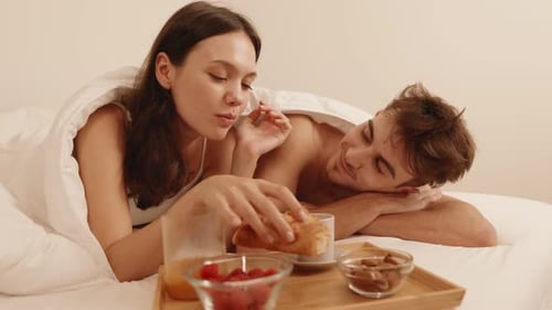 Affectionate Couple Enjoying Breakfast in Bed Together