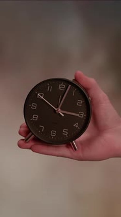 A Vintage Clock Held in Hand Against a Blurred Background Creating an Intriguing Focal Point