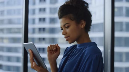 Young Woman Uses Tablet Device by Office Window