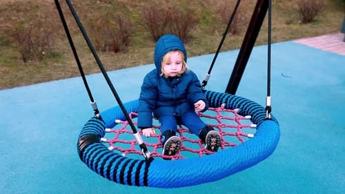 Child Plays on Large Swing in Playground During Sunny Day