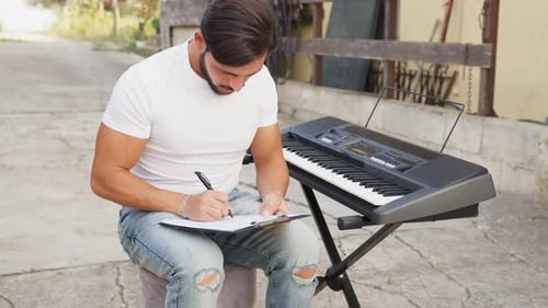 Young Man Composing Song on Electric Piano