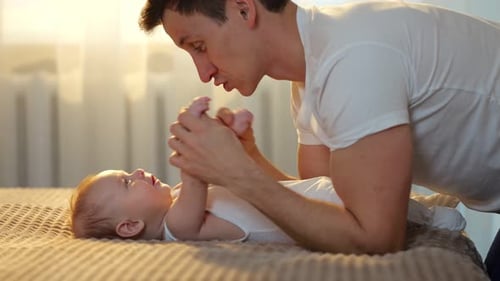 Loving Father Plays with Adorable Infant on Bed