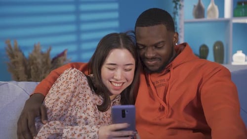 Affectionate Couple Relaxing on Couch with Mobile Phone