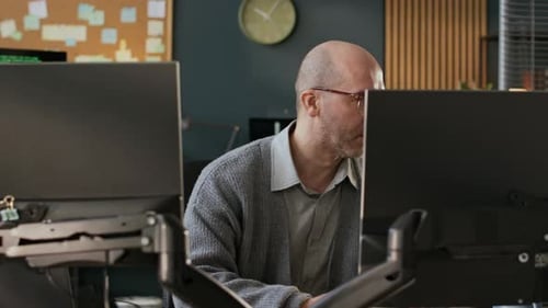 Konzentrierter männlicher Programmierer mittleren Alters, der Software auf dem PC im Büro entwickelt