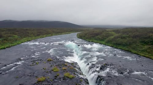 Aerial Flight Over Bruarfoss Iceland Waterfall River. Drone Backward Over Cascading Water Landscape.