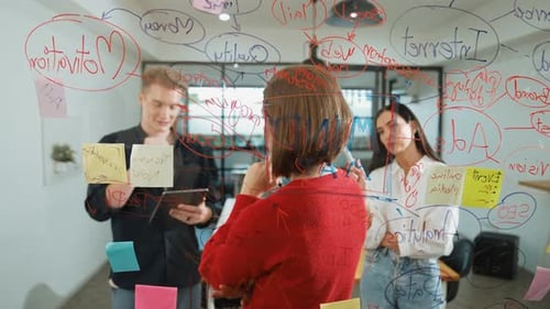 Team Brainstorming and Planning on Glass Whiteboard in Office