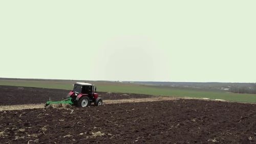 Red tractor plowing the field in Ukraine