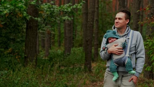 Young Father with His Newborn Baby in a Sling Walking in the Autumn Forest The Concept of a Happy