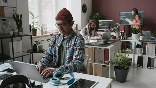 Geeky Male Programmer Typing on Laptop in Startup Office