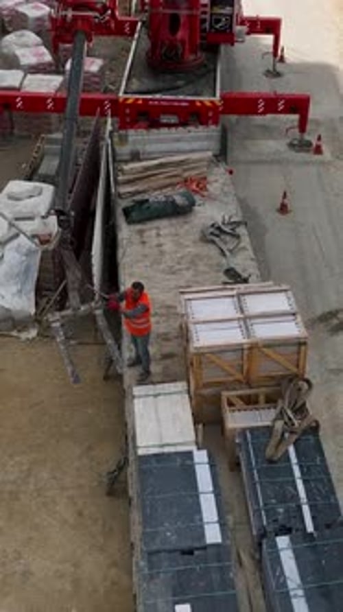 Vídeo vertical sobre el terreno del edificio Vista aérea de una grúa descargando carga con constructores en