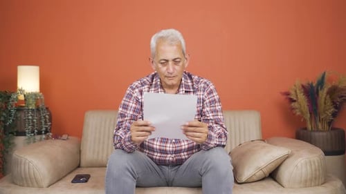 Man Reading Good News Letter on Sofa