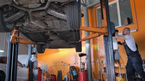 Mechanic Working on Car Lift in Repair Shop