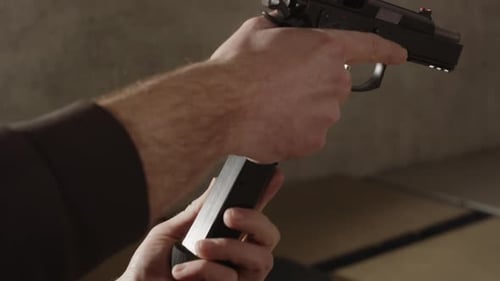 Loaded magazine being put into 9mm pistol and slide closing in slow motion