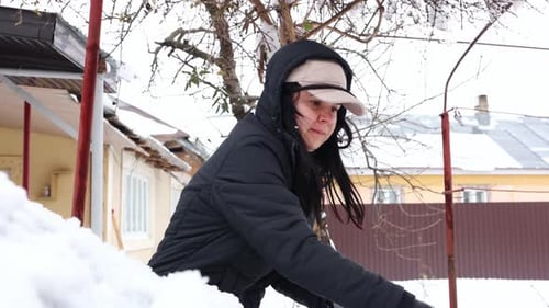 Woman Removing Snow in Suburban Winter Setting