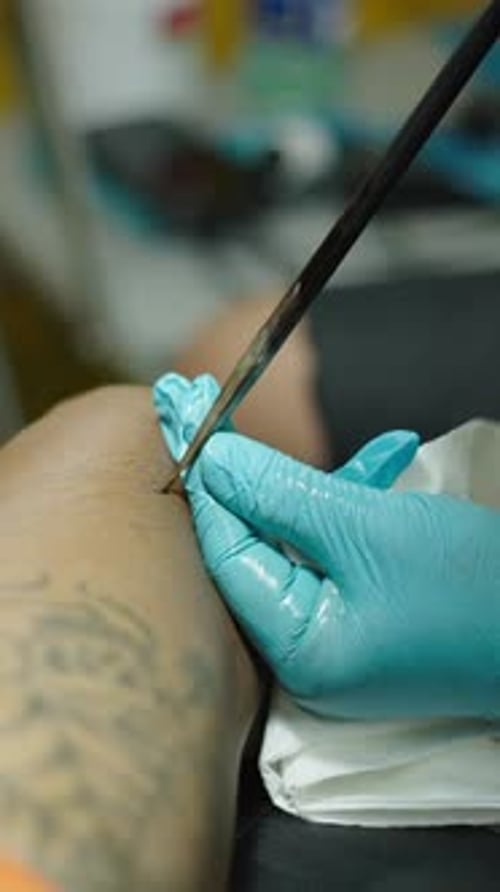 Close Up Shot of a Traditional Tattoo Artist Performing a Tattoo on Client Leg Creative Concept
