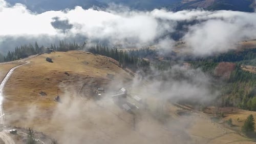 Aerial View of a Beautiful Rural Mountain Village Covered in Morning Fog Dirt Road Passing Through