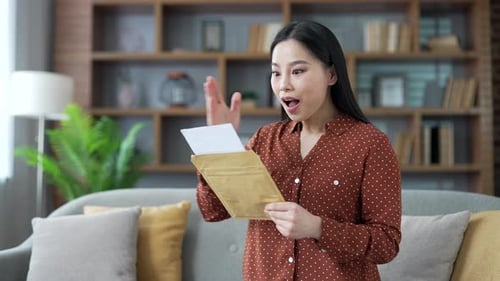Excited Woman Opens Letter and Reacts with Surprise