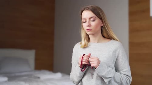 Young Woman Holds Rosary Beads for Prayer