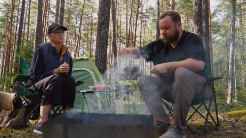 Couple grilling meat on a barbecue in a pine forest