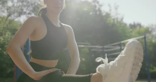 Woman Stretching Leg in Park on Sunny Day