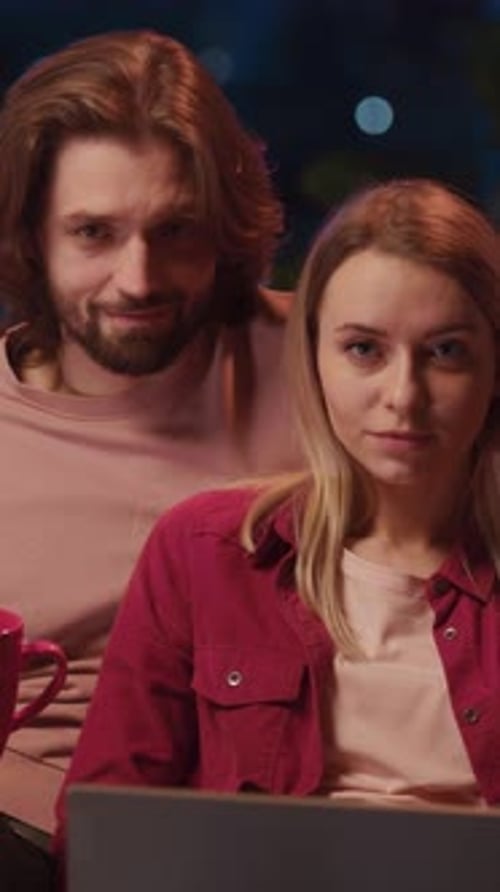 Smiling Couple Using Laptop Indoors at Night