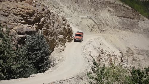 Carro SUV laranja se movendo lentamente na estrada da montanha.