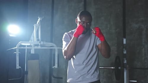 Fitness Workout in Gym African Man Fighter Preparing for Fight Punching with Red Boxing Wraps Sports