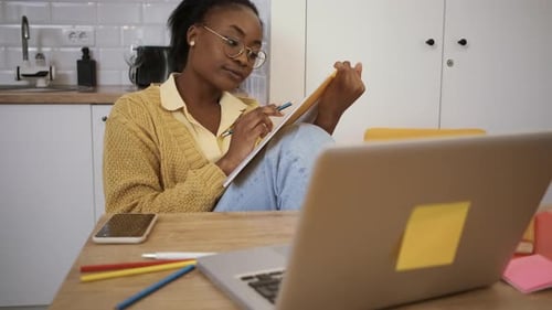 Woman taking notes at kitchen table