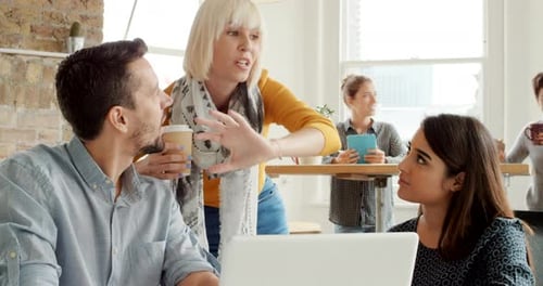 Team Collaborates Around Laptop in Modern Workplace