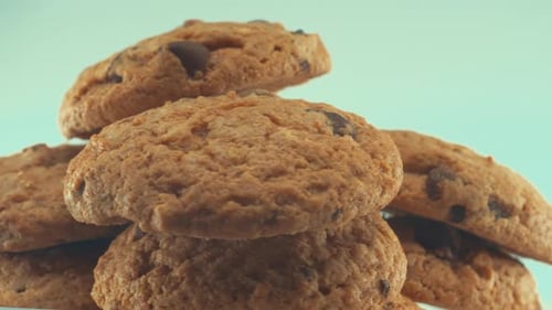 A macro close up shot of a white plate full of tasty chocolate chip cookies, on a 360 rotating stand