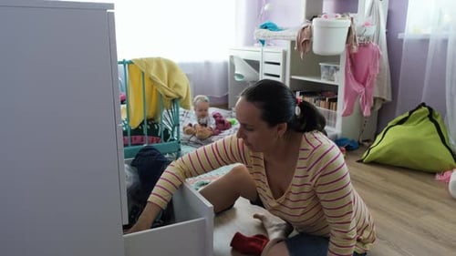 Woman Sorting Clothes in Child's Room