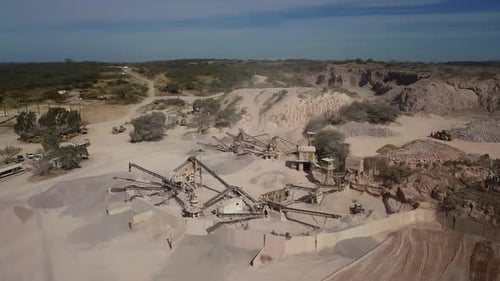 aerial view of a working stone quarry with stone crushers, bulldozers, trucks in a natural environme
