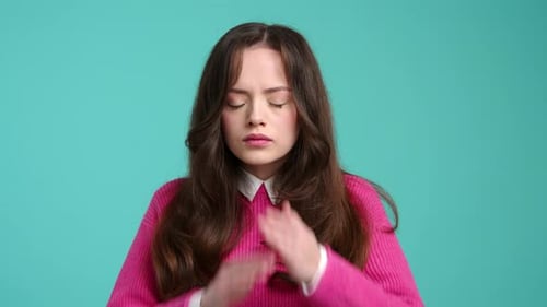 Young Woman Covers Eyes on Teal Background