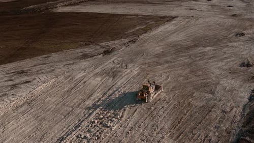 Una foto de un Zumbido a ciento ochenta grados de un tractor multiterreno compactando tierra en una construcción