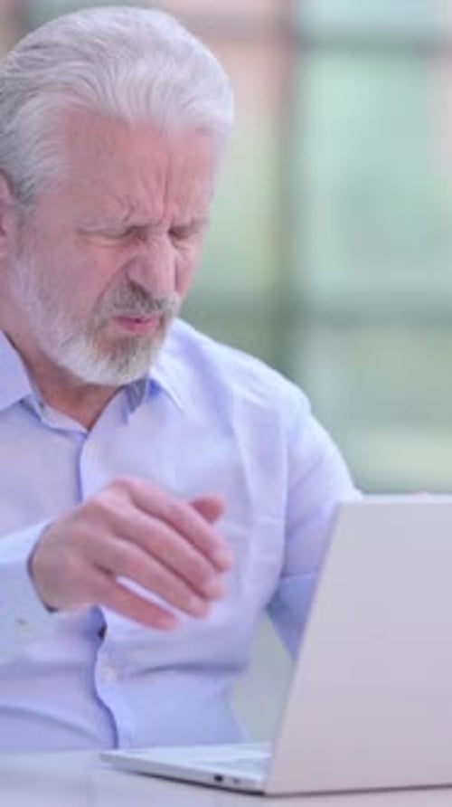 Mature Man with Headache Uses Laptop at Desk