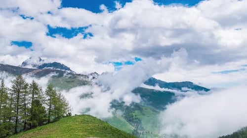 Time lapse, moving clouds in the valley below mountain ridges and peaks of the Alps. Majestic snow c