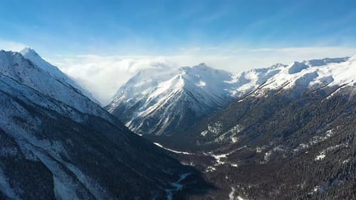 Air flight through mountain clouds over beautiful snow-capped peaks of mountains and glaciers.