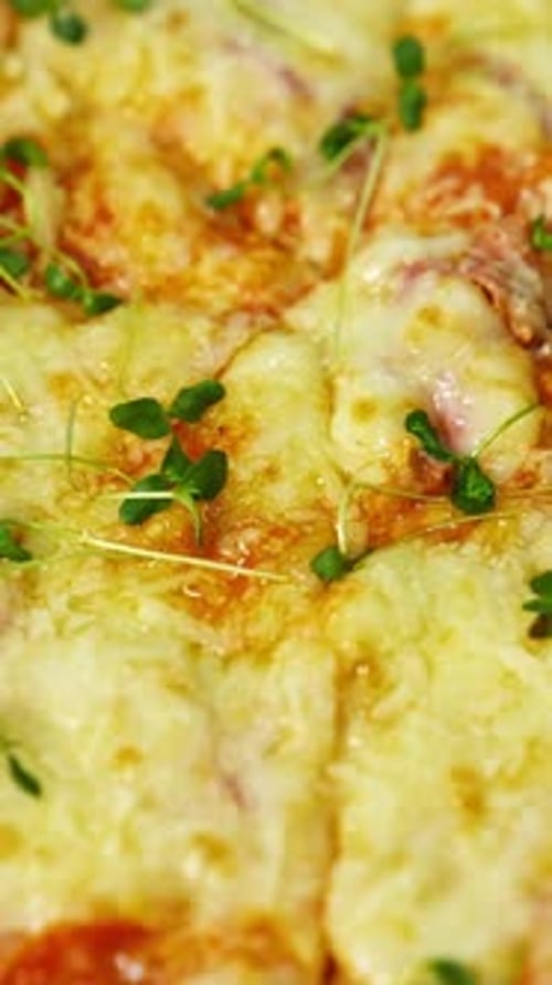 Delicious pizza. Melted cheese and green sprouts on pizza. Appetizing pizza spinning on the table