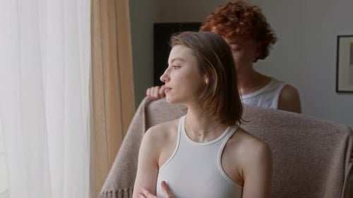 Hombre cubriendo a su novia con una manta y abrazándola en un día frío en casa