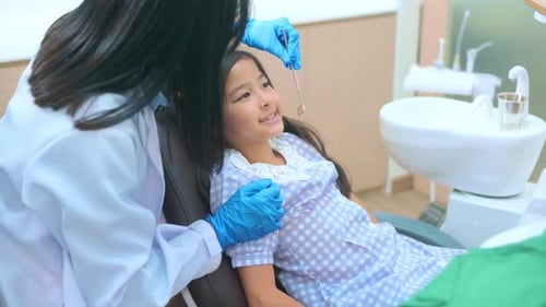 A little cute girl having teeth examined by dentist in dental clinic